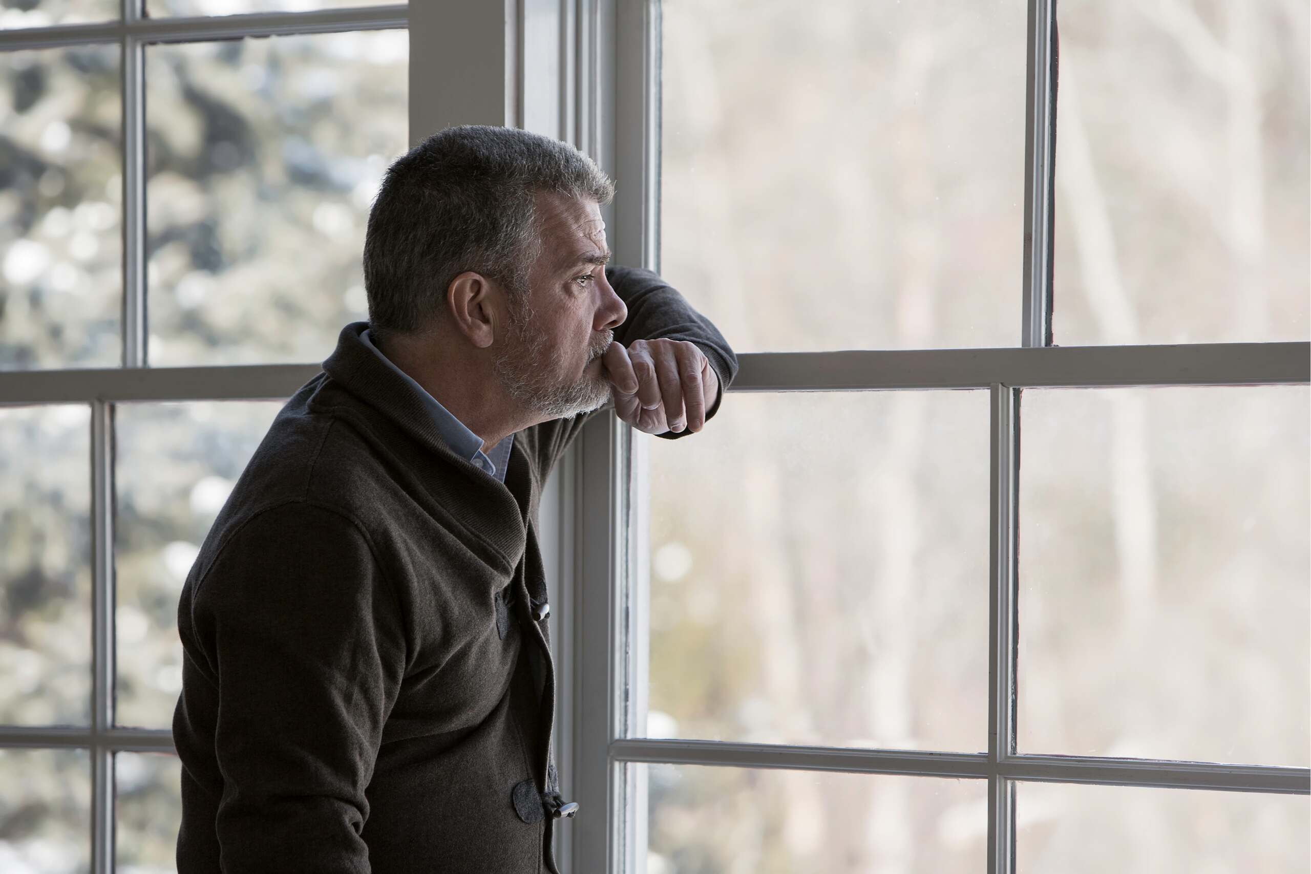 A man looking sadly out of his window